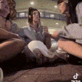 a group of people are sitting on the ground with a tik tok logo in the corner