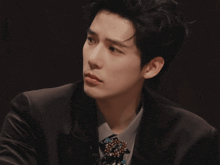 a man wearing a suit and tie with a brooch on his neck