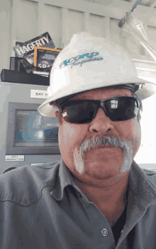 a man wearing a hard hat and sunglasses has a hagerty magazine on top of him