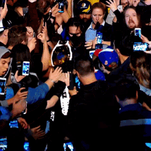 a crowd of people are gathered around a man wearing a yellow shirt that says ' golden state warriors ' on it