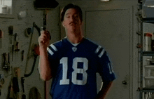 a man wearing a football jersey with the number 18 on it is holding a gun .