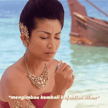 a woman wearing a necklace and a ring with the words mengimbau kembali kejahilan silam on the bottom