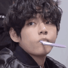 a young man with curly hair is brushing his teeth with a toothbrush .