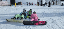 a group of people laying on a snowy slope with a snowboard that says aozz