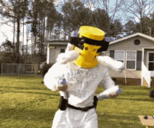 a man wearing a yellow mask and a white shirt that says stay back is standing in front of a house