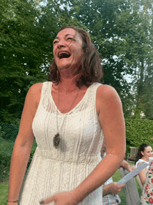 a woman in a white lace dress is laughing with her mouth open