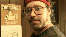 a man wearing glasses and a red headband is standing in front of a commando calendar