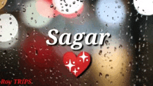 a heart with the name sagar on it is sitting on a window with rain drops .