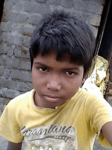 a young boy wears a yellow t-shirt that says brassland