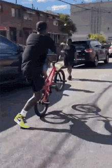 a man is riding a red bike down a street with a license plate that says ' jc ' on it