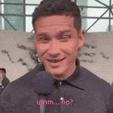 a man is smiling while talking into a microphone and the words umm ... no appear on the screen behind him .