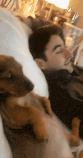 a man is laying in bed with a puppy on his chest