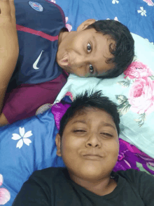 two young boys laying on a bed with one wearing a nike jersey