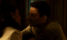 a man and woman are kissing in a dark room