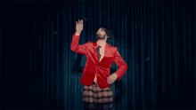 a man in a red jacket and plaid skirt is dancing