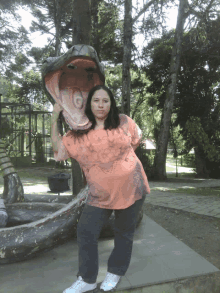 a woman stands in front of a statue of a snake