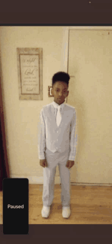 a young boy in a suit is standing in front of a wall with a sign that says " look "