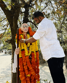 a man decorates a statue with flowers and garlands