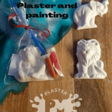 a monkey , a lion and an elephant are sitting on a wooden table with a bag of plaster and paint .