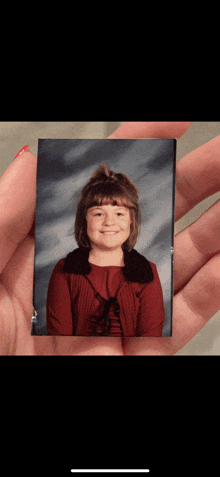 a woman is holding a picture of a young girl