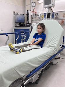 a little girl in a blue dodgers shirt sits in an emergency room