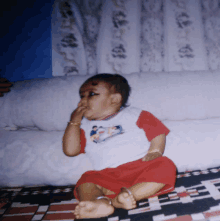 a baby is sitting on a couch with his hand on his face