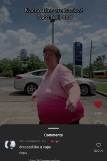 a woman in a pink shirt is standing in front of a taco bell restaurant