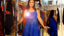 a woman is trying on a blue dress in front of a mirror in a store