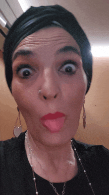 a woman wearing a black turban making a funny face with her tongue out