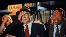 a man in a suit and tie is covering his face in front of a sign that says danger