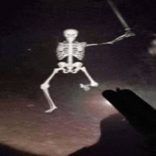 a skeleton is holding a sword and a flashlight is shining on it