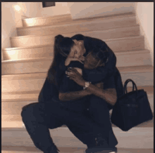 a man and a woman are sitting on a set of stairs and hugging