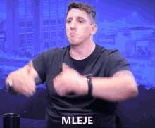 a man wearing a black shirt with the word mleje on the front