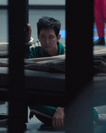 a man in a green and white striped shirt is kneeling on the floor