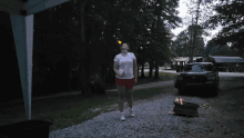 a woman standing in front of a fire pit holding a bottle of beer