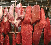 a bunch of raw meat is hanging from a rack .