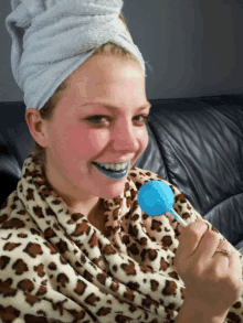 a girl with a towel wrapped around her head is holding a blue lollipop