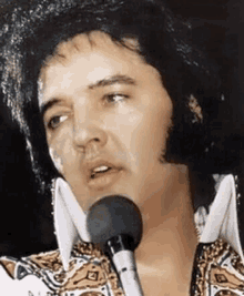 elvis presley is singing into a microphone in a close up of his face