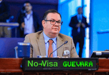 a man sits at a desk with a sign that says no visa guevara