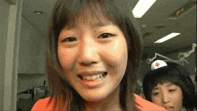 a girl with a red cross on her hat smiles for the camera