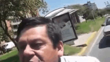 a man is standing on the side of the road next to a bus stop .