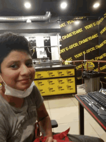 a boy wearing a mask in front of a wall that says yeny e-spor okmeydani