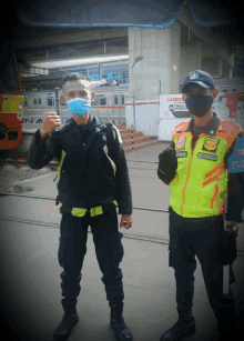 a man wearing a mask is standing next to a man wearing a vest that says stasi