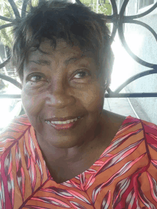 a woman in a pink and orange striped shirt smiles for the camera