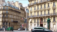 a car is driving down a street in front of a building with a green van parked in front of it