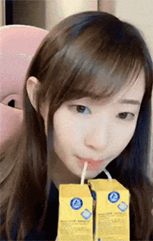 a girl drinking from two cartons with a straw