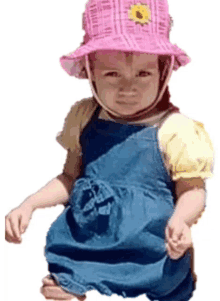 a little girl wearing overalls and a pink hat