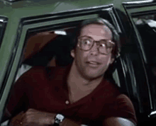 a man wearing glasses is driving a car