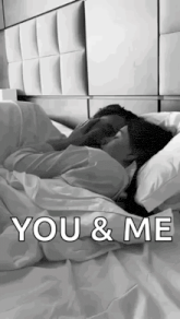 a black and white photo of a man and woman hugging in bed .