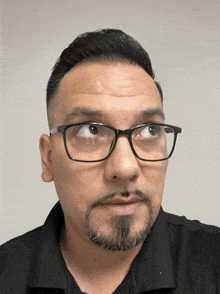 a man wearing glasses and a black shirt is looking at the camera